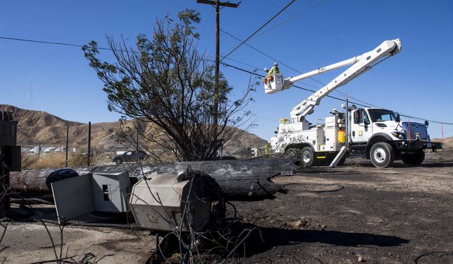 SoCal Edison workers replace power lines that were damaged from the Tick Fire, Thursday, Oct. 25, 2019, in Santa Clarita, Calif. An estimated 50,000 people were under evacuation orders in the Santa Clarita area north of Los Angeles as hot, dry Santa Ana winds howling at up to 50 mph (80 kph) drove the flames into neighborhoods (AP Photo/ Christian Monterrosa)