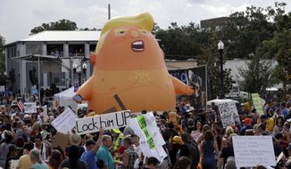 In this June 18, 2019, file photo, an inflatable Baby Trump balloon towers over protesters during a rally in Orlando, Fla. A coalition of liberal groups is hoping to take the fight over House Democrats’ impeachment inquiry of President Donald Trump to the streets. (AP Photo/Chris O&#x27;Meara, File)