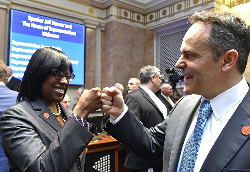FILE - In this Jan. 3, 2017 file photo, Kentucky Gov. Matt Bevin, right, and Kentucky Lt. Governor Jenean Hampton bump fists as they await the swearing in of Jeff Hoover as Speaker of the Kentucky House of Representatives in Frankfort, Ky. Kentucky Gov. Matt Bevin has won another round of a legal fight with his lieutenant governor over who wields hiring and firing authority over the lieutenant governor’s staff. A judge ruled Friday, Oct. 25, 2019 that the Republican governor has “superseding authority” to hire and fire employees assigned to the lieutenant governor’s office. (AP Photo/Timothy D. Easley, File)
