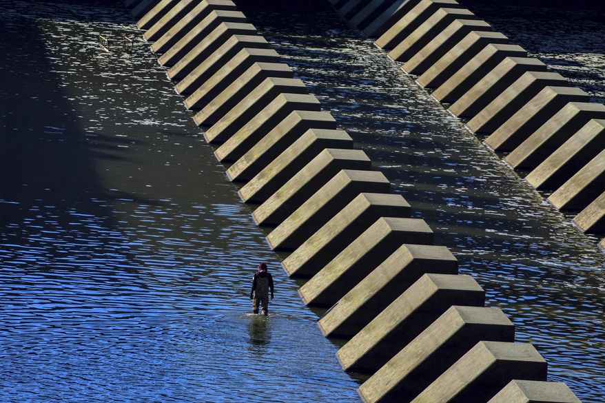 An angler walks in Harlan County Lake and recreation area Sunday, Oct 13, 2019, in rural Harlan County, Neb. (Joe Dejka/The World-Herald via AP)