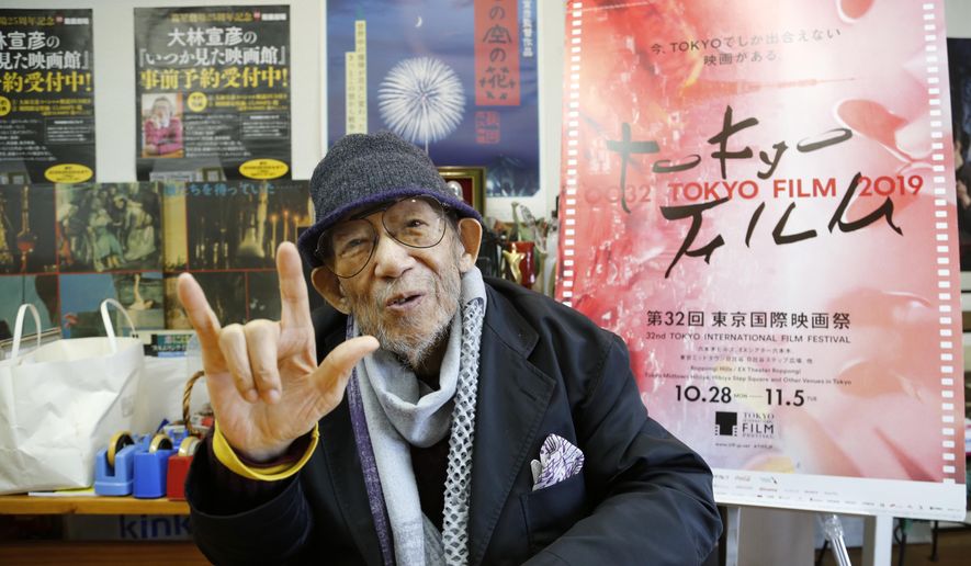 In this Oct. 11, 2019, photo, Japanese director Nobuhiko Obayashi holds up his hand in the sign language of “I love you” to stress that is an important message in his films, during an interview at his studio in Tokyo. Obayashi has been diagnosed with fatal lung cancer, but his confrontation with death began so long ago it has characterized his entire four decades of filmmaking. Obayashi has stayed true to himself during that whole time, producing more than 40 movies and thousands of TV shows, commercials and other video, devoted to sending the same message, over and over, to warn the world of the horrors of war. (AP Photo/Yuri Kageyama)