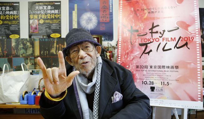 In this Oct. 11, 2019, photo, Japanese director Nobuhiko Obayashi holds up his hand in the sign language of “I love you” to stress that is an important message in his films, during an interview at his studio in Tokyo. Obayashi has been diagnosed with fatal lung cancer, but his confrontation with death began so long ago it has characterized his entire four decades of filmmaking. Obayashi has stayed true to himself during that whole time, producing more than 40 movies and thousands of TV shows, commercials and other video, devoted to sending the same message, over and over, to warn the world of the horrors of war. (AP Photo/Yuri Kageyama)