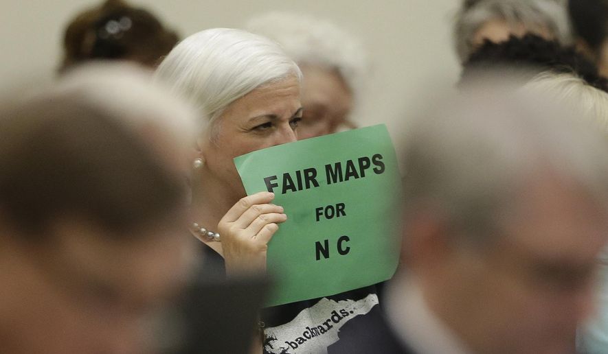 In this July 26, 2017 photo, a member of the gallery tries to display her sign while lawmakers convene during a joint select committee meeting on redistricting in Raleigh, N.C. North Carolina judges on Monday blocked the state's congressional map from being used in the 2020 elections, ruling that voters had a strong likelihood of winning a lawsuit that argued Republicans unlawfully manipulated district lines for partisan gain. (AP Photo/Gerry Broome)