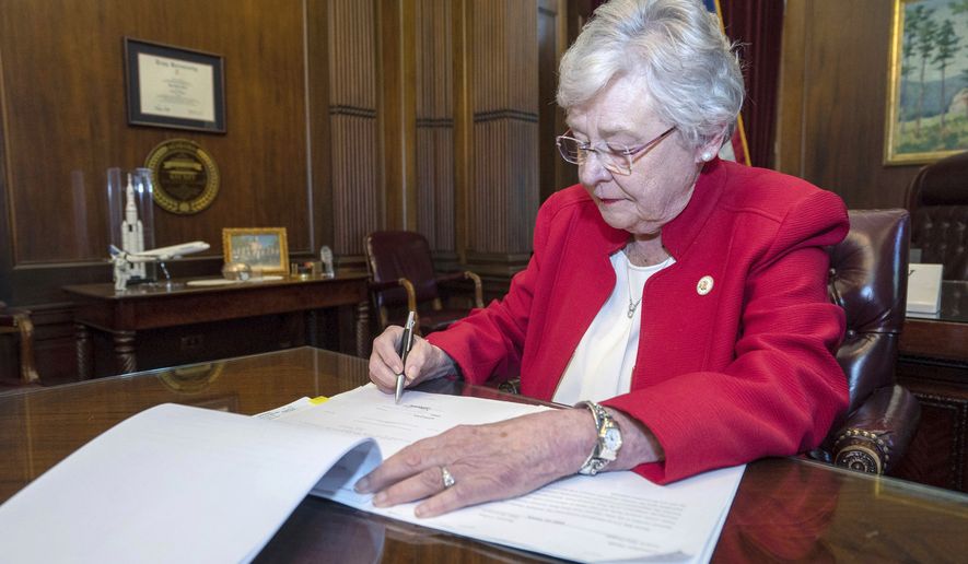 This Wednesday, May 15, 2019, photo released by the state shows Alabama Gov. Kay Ivey signing a bill that virtually outlaws abortion in the state, in Montgomery, Ala. U.S. District Judge Myron Thompson on Tuesday, Oct. 29, 2019, has blocked an Alabama abortion ban that would have made the procedure a felony at any stage of pregnancy in almost all cases. (Hal Yeager/Alabama Governor's Office via AP) **FILE**