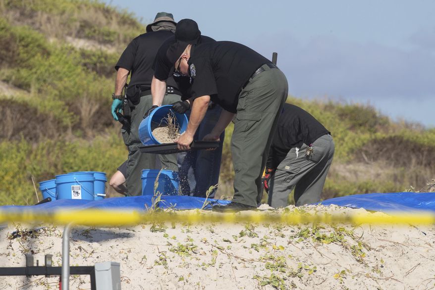 Several state agencies conduct an investigation on a Padre Island, Texas beach in Kleberg County after human remains were found on Monday, Oct. 28, 2019. The Kleberg County Sheriff's Office says a deputy located a woman's remains Sunday in a shallow grave on Padre Island, near Corpus Christi. Chief Deputy Jaime Garza says a man's body was discovered Monday beneath the first body. (Courtney Sacco/Corpus Christi Caller-Times via AP)
