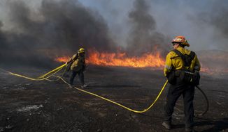 Firefighters work to prevent flames from reaching nearby homes while battling the Easy Fire, Wednesday, Oct. 30, 2019, in Simi Valley, Calif.  It has chewed through brush and trees near suburbs, horse ranches and the Ronald Reagan Presidential Library. (AP Photo/Christian Monterrosa)