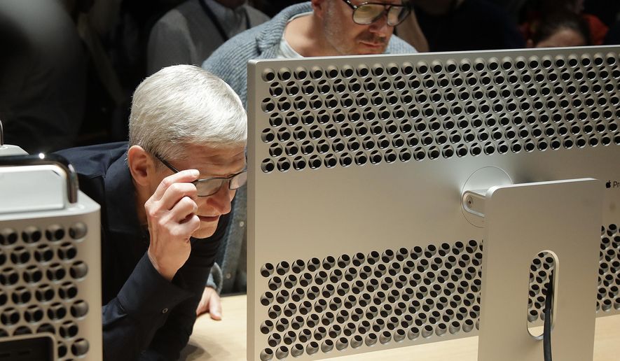 FILE - In this June 3, 2019, file photo Apple CEO Tim Cook, left, and chief design officer Jonathan Ive look at a Mac Pro in the display room at the Apple Worldwide Developers Conference in San Jose, Calif. Apple Inc. reports financial earns on Wednesday, Oct. 30. (AP Photo/Jeff Chiu, File)