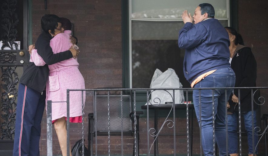 Neighbors grieve near a home where four people were found shot dead Wednesday, Oct. 30, 2019, in west Philadelphia. Police say a man is in custody following the deaths of his mother, stepfather and two brothers, including a 6-year-old boy, who were found shot in the home. (Charles Fox/The Philadelphia Inquirer via AP)