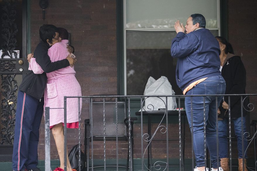 Neighbors grieve near a home where four people were found shot dead Wednesday, Oct. 30, 2019, in west Philadelphia. Police say a man is in custody following the deaths of his mother, stepfather and two brothers, including a 6-year-old boy, who were found shot in the home. (Charles Fox/The Philadelphia Inquirer via AP)