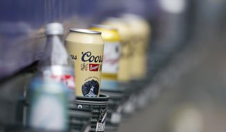 FILE - In this June 3, 2018, file photo empty cans of Coors beer sit in beverage holders on the backs of box seats after the ninth inning of a baseball game in Denver. Molson Coors Brewing Co. is laying off 500 workers worldwide and restructuring its operations as it faces declining beer sales. (AP Photo/David Zalubowski, File)