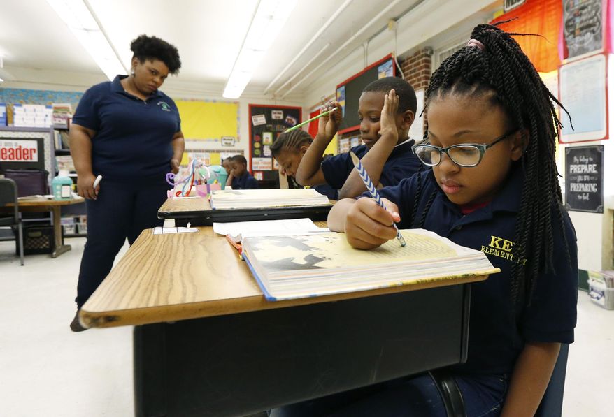 In this April 18, 2019 file photo, Elize'a Scott, a Key Elementary School third grade student, right, reads under the watchful eyes of teacher Crystal McKinnis, left in Jackson, Miss. Nationally, lower-performing students are doing worse in math and reading, thus dragging down overall results on the Nation's Report Card. Mississippi and the District of Columbia showed gains, along with some other big-city school districts. (AP Photo/Rogelio V. Solis, File) **FILE**