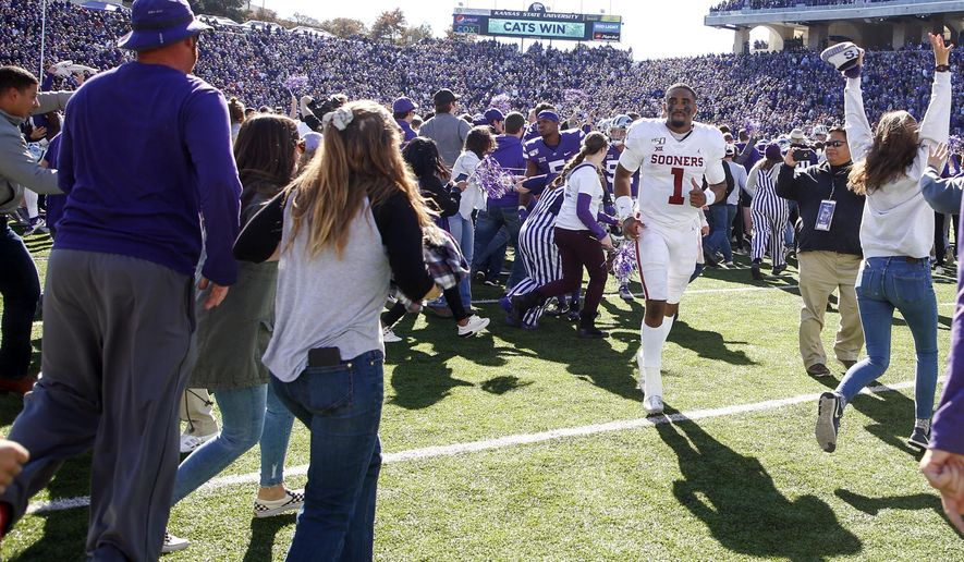 Kansas State fans storm the field as Oklahoma quarterback Jalen Hurts (1) attempts to head towards the locker room after the Sooners loss to the Wildcats in an NCAA football game at Bill Snyder Family Stadium in Manhattan, Kan., Saturday, Oct. 26, 2019. (Ian Maule/Tulsa World via AP)