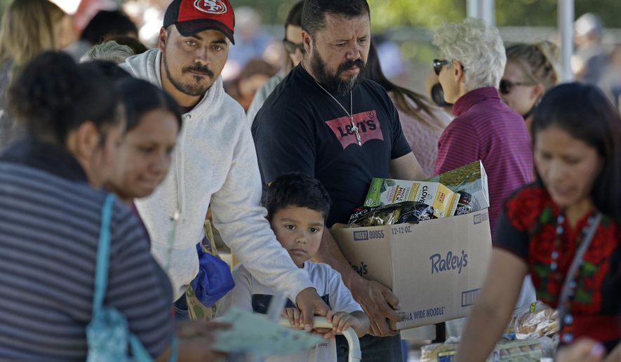 People gather items during a free food distribution for migrant workers evacuated because of the Kincade Fire Thursday, Oct. 31, 2019, in Healdsburg, Calif. (AP Photo/Charlie Riedel)