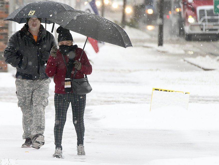 Hevibeta Sanchez and Jose Ramos both of La Salle, hold umbrellas as they walk through the falling snow near the corner of Gooding and Third Streets in La Salle, Ill., Thursday, Oct. 31, 2019. (Scott Anderson/Daily Chronicle via AP)