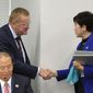FILE - In this Wednesday, Oct. 30, 2019, file photo, Tokyo Gov. Yuriko Koike, right, shakes hands with International Olympic Committee member John Coates during their meeting in Tokyo. The IOC abruptly announced two weeks ago it was moving next year’s Olympic marathon from Tokyo to the northern city of Sapporo. Coates, who supervises Tokyo preparations, said the decision was made based on “what we saw in Doha, Qatar.” (Kyodo News via AP)