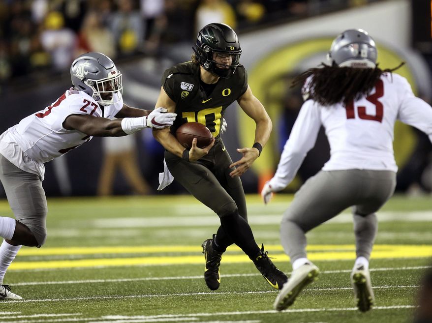 Washington State's Willie Taylor III, left, and Jahad Woods, right, converge on Oregon's Justin Herbert for a sack during the second quarter of an NCAA college football game Saturday, Oct. 26, 2019, in Eugene, Ore. (AP Photo/Chris Pietsch)