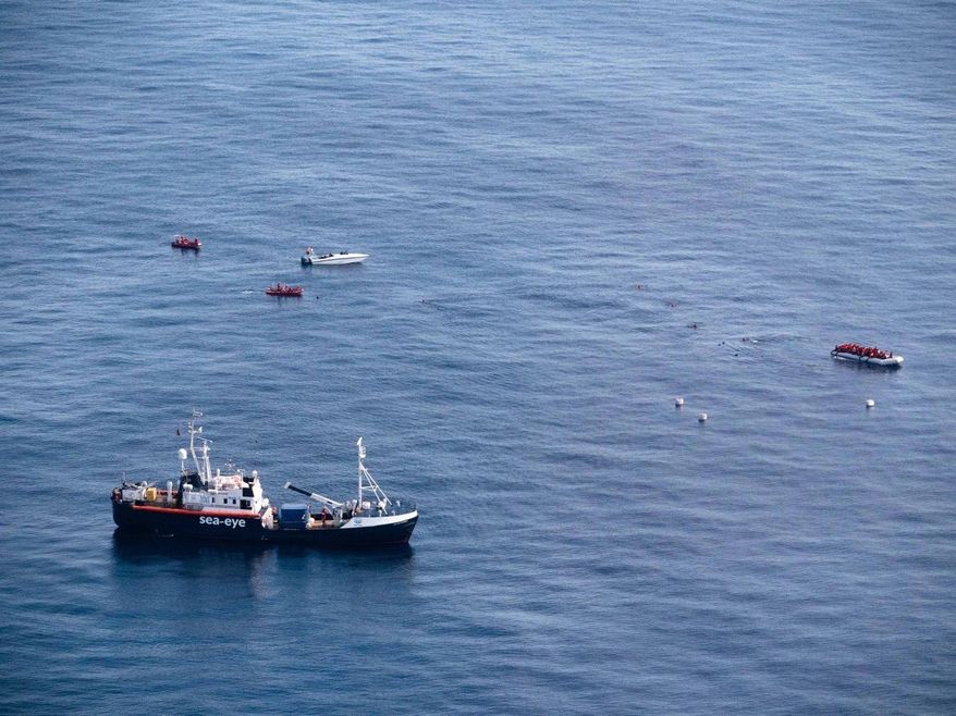 In this photo taken on Saturday, Oct. 26, 2019, The Alan Kurdi rescue ship, foreground, approaches a dinghy boat full of migrants, top right, as a Libya-flagged speedboat, top left, sails around, off the coast of Libya. A humanitarian aid group said gunmen on Libya-flagged speedboats threatened the crew of its rescue ship Alan Kurdi and the migrants it was rescuing Saturday, firing shots into the air and water. Sea-Eye's spokesman Gorden Isler told The Associated Press that the unprecedented incident on the Mediterranean Sea was a "total shock" for the rescue crew, but that they managed to bring all the roughly 90 migrants on board. (Sea-Eye via AP)