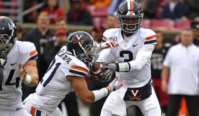 Virginia quarterback Bryce Perkins (3) makes a handoff to running back Wayne Taulapapa (21) during the first half of an NCAA college football game in Louisville, Ky., Saturday, Oct. 26, 2019. (AP Photo/Timothy D. Easley)