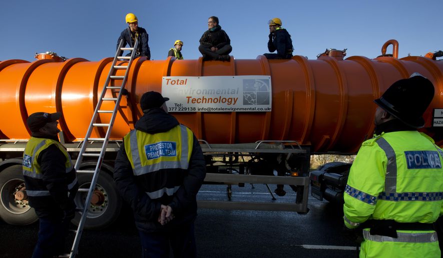 In this Monday, Jan. 13, 2014 file photo, police prepare to remove a protestor from the top of a vehicle waiting to enter an exploratory drill site for the controversial gas extraction process known as fracking at Barton Moss in Manchester, England. The British government announced Saturday, Nov. 2, 2019, that it will no longer allow fracking because of new scientific analysis that casts doubts on the safety of the controversial practice, but some critics said the measure falls short because it is not a permanent ban. (AP Photo/Jon Super, File)