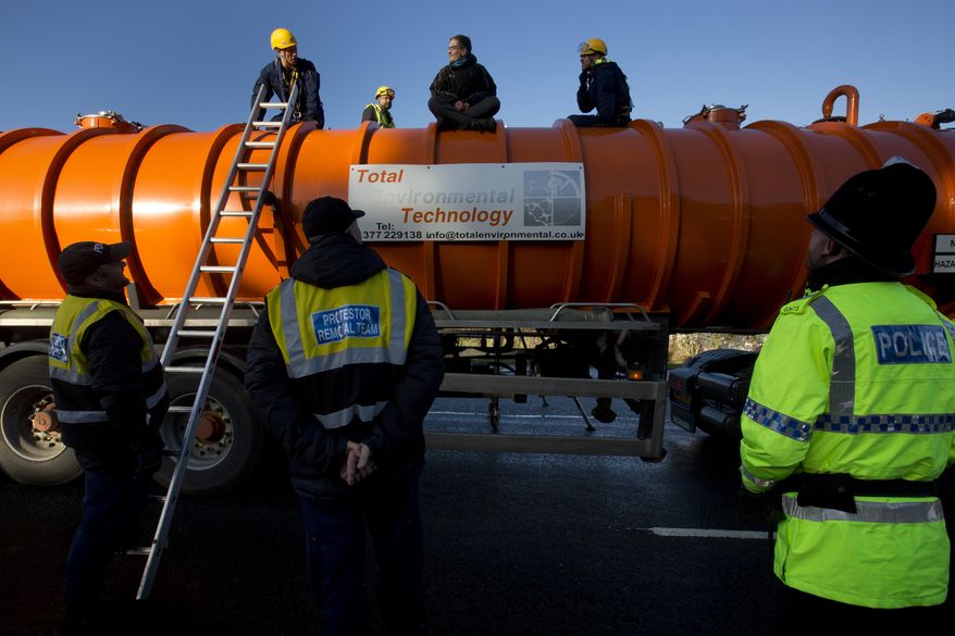 In this Monday, Jan. 13, 2014 file photo, police prepare to remove a protestor from the top of a vehicle waiting to enter an exploratory drill site for the controversial gas extraction process known as fracking at Barton Moss in Manchester, England. The British government announced Saturday, Nov. 2, 2019, that it will no longer allow fracking because of new scientific analysis that casts doubts on the safety of the controversial practice, but some critics said the measure falls short because it is not a permanent ban. (AP Photo/Jon Super, File)