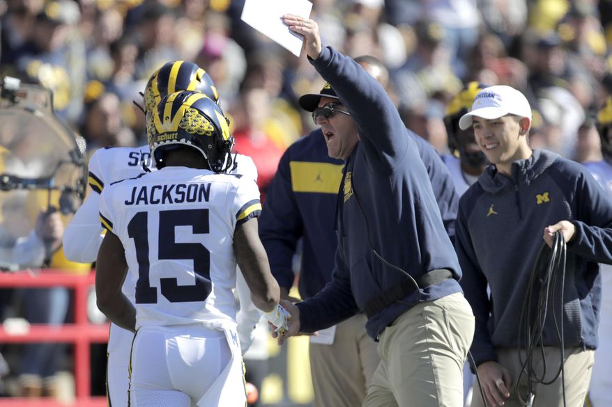 Michigan head coach Jim Harbaugh, center, congratulates Giles Jackson after he returned the opening kickoff from Maryland for a touchdown during the first half of an NCAA college football game, Saturday, Nov. 2, 2019, in College Park, Md. (AP Photo/Julio Cortez)