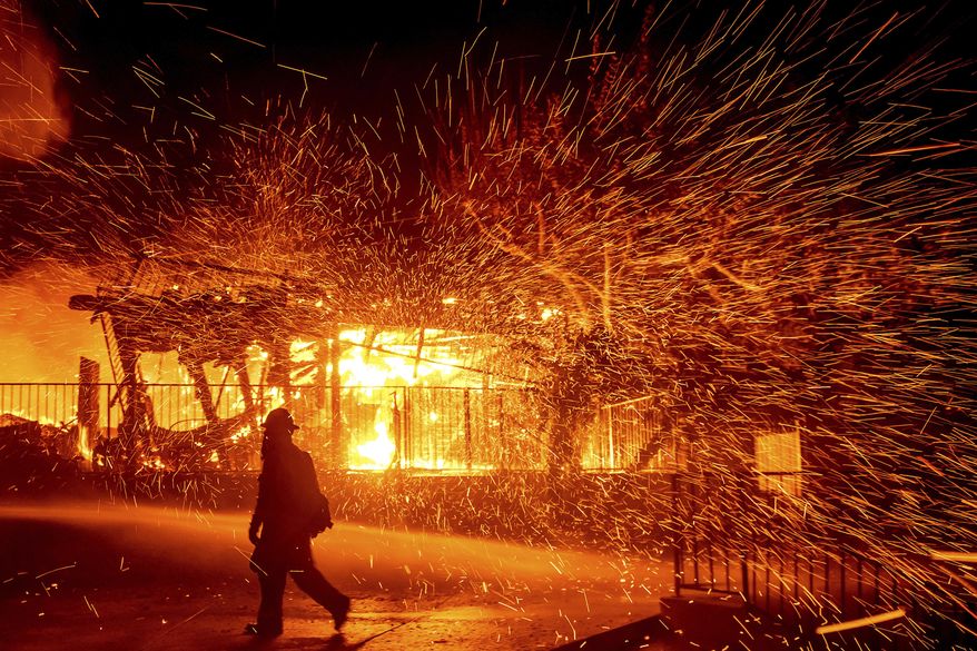 A firefighter passes a burning home as the Hillside fire burns in San Bernardino, Calif., Oct. 31, 2019. (AP Photo/Noah Berger)