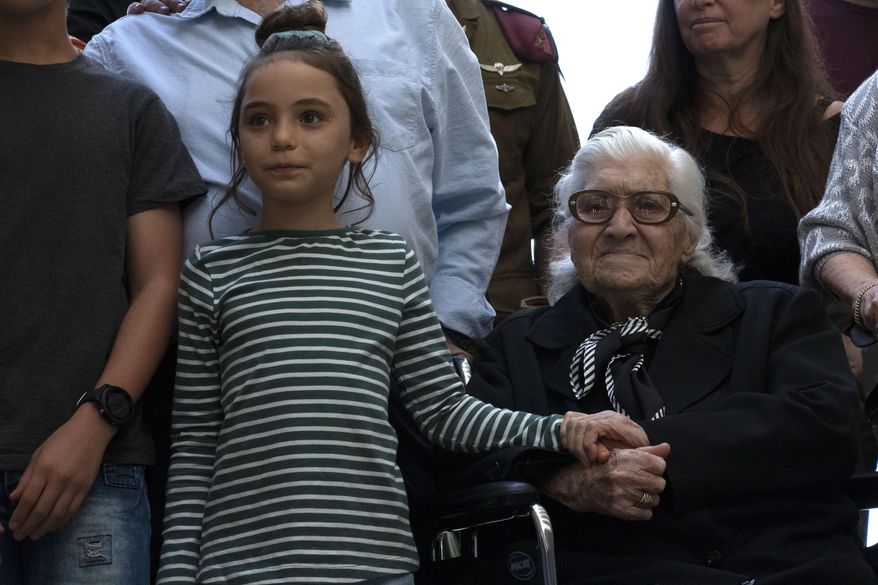 Melpomeni Dina holds the hand of an Israeli girl during a reunion at the Yad Vashem Holocaust memorial in Jerusalem, Sunday, Nov. 3, 2019. Dina, a 92-year-old Greek woman who rescued a Jewish family during the Holocaust has been reunited with two of the people she saved and dozens of their family members. Once a regular ritual, such reunions are quickly disappearing due to the advanced age of the rescuers and survivors. (AP Photo/Patty Nieberg)