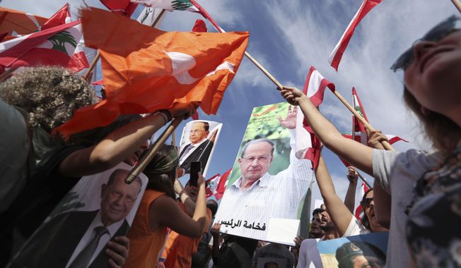 Supporters of Lebanese President Michel Aoun hold his pictures and Lebanese flags during a protest near the presidential palace in the Beirut suburb of Baabda, Lebanon, Sunday, Nov. 3, 2019. Thousands of people are marching to show their support for Aoun and his proposed political reforms that come after more than two weeks of widespread anti-government demonstrations. (AP Photo/Hassan Ammar)