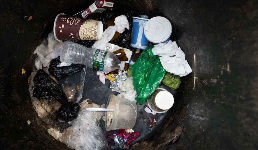 A plastic water bottle and plastic bags are seen discarded with other garbage in a corner trash can in the East Village neighborhood of Manhattan, Wednesday, March 27, 2019 in New York. Two New York lawmakers say Wednesday that they're optimistic that a ban on single-use plastic shopping bags could be included in the spending plan that's due Sunday. (AP Photo/Mary Altaffer)