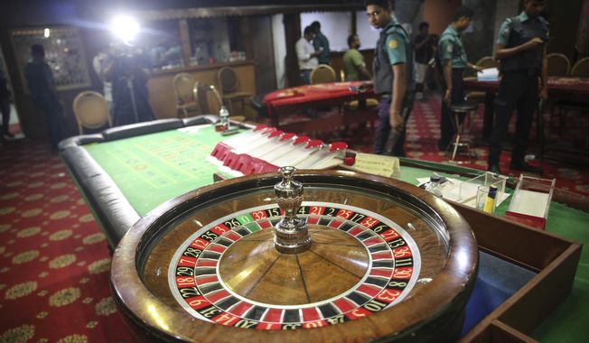 In this Sept. 22, 2019, photo, police officers inspect seized gambling equipment at Victoria Sporting Club in Dhaka, Bangladesh. Security officials in Bangladesh are on the hunt for cash, gold and illicit weapons in a crackdown Prime Minister Sheikh Hasina ordered on illegal casinos, rooting out corruption among political elites that critics say has been allowed to flourish in a troubled democracy with no effective opposition. (AP Photo/Mahmud Hossain Opu)