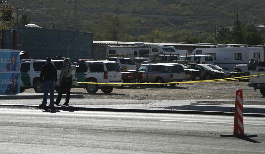 A local sheriff's deputy points with a water bottle to part of a crime scene of a fatal shooting on Monday, Nov. 4, 2019, in Sunland Park, New Mexico, a suburb of El Paso, Texas. Customs and Border Protection officials said an armed man was fatally shot by a Border Patrol agent after the gunman opened fire. The scene is about a mile from the U.S.-Mexico border. (AP Photo/Cedar Attanasio)