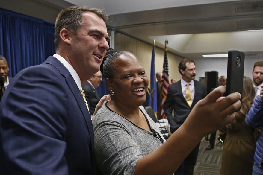 Oklahoma Gov. Kevin Stitt, left, poses for a selfie with Joy Block, right, of Tulsa, Okla., following a news conference to announce that Oklahoma will release more than 400 inmates after the board approved what they say is the largest single-day mass commutation in U.S. history, Friday, Nov. 1, 2019, in Oklahoma City. Block is the founder of Walters Way Regaining Your Life Foundation, a Tulsa re-entry program for offenders. (AP Photo/Sue Ogrocki)