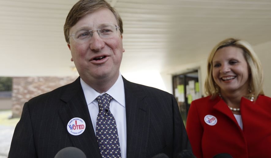 Lt. Gov. Tate Reeves, left, speaks with reporters while his wife Elee Reeves, laughs at his response outside their Flowood, Miss., voting precinct, Tuesday, Nov. 5, 2019. Reeves, the Republican nominee for governor is in one of the state&#39;s most hotly contested governor&#39;s race since 2003. Voters will also select six other statewide officials and decide on a host of legislative and local offices. (AP Photo/Rogelio V. Solis)