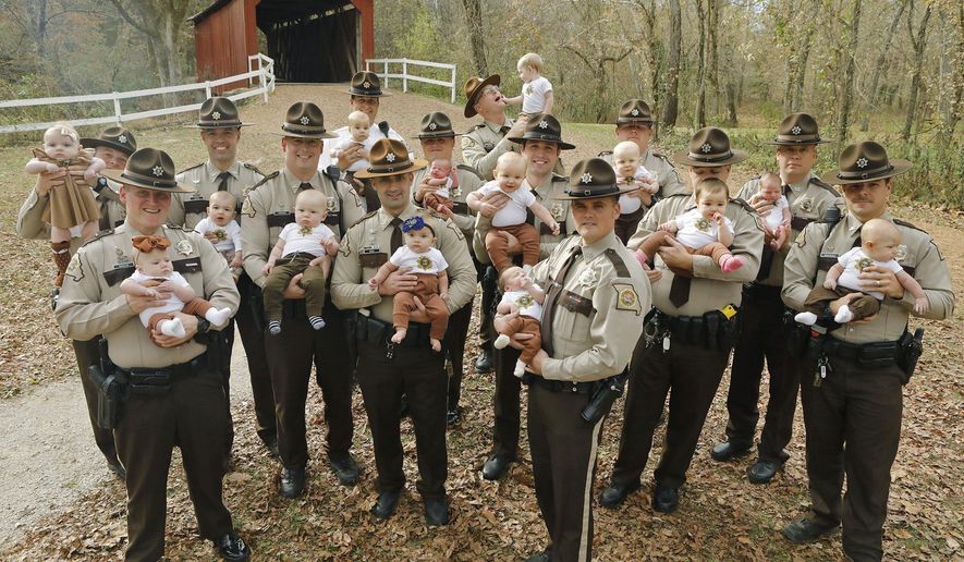 In this Nov. 4, 2019, photo fourteen Jefferson County Sheriffs Deputies pose for a photo with their babies at the Sandy Creek Covered Bridge in Jefferson County, Mo. They are from left, with their babies: Adam Lambrich with Lilliana; AJ Kausler with Lucy; Matt Moore with Luca; Scott Ehrhard with Hudson; Andy Sides with Carter; Greg Bohn with Evelyn; Dustin Isenhart with Kash; Nick Gamm with Gweneth; Colby McCreary with Sawyer; Cody Cawvey with Micah; Shawn Loness with Connor; Andrew Griffon with Kinsley; Kevin Karl with Kade; and Roger Waeckerle with Wyatt. (J.B. Forbes/St. Louis Post-Dispatch via AP)