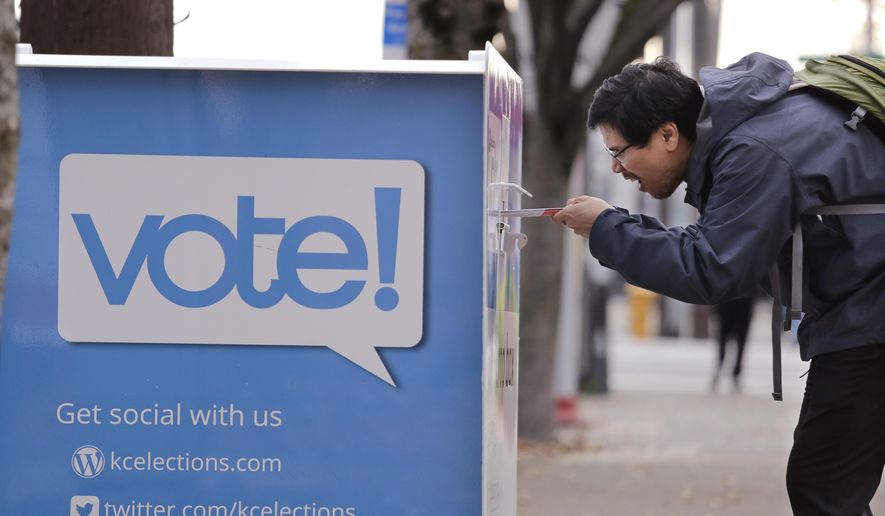 Watcharin Photangtham carefully eyes the slot as he drops ballots for he and his husband into a ballot drop box Monday, Nov. 4, 2019, in Seattle. Voters in Washington state have a crowded ballot to fill out for this week's election, with a referendum on affirmative action and an initiative on the price of car tabs among the things they are being asked to decide. (AP Photo/Elaine Thompson)