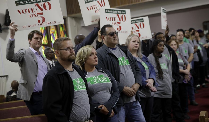 In this Sunday, Nov. 3, 2019, photo, people wearing "Save The Paseo" shirts stand among attendees at a rally to keep a street named in honor of Dr. Martin Luther King Jr. at Paseo Baptist Church in Kansas City, Mo. In January, the City Council voted to rename one of the city's main boulevards, The Paseo, after King, but many in the community want the old name back. A petition drive put the issue on the Nov. 5 ballot pitting neighbors against each other. (AP Photo/Charlie Riedel)