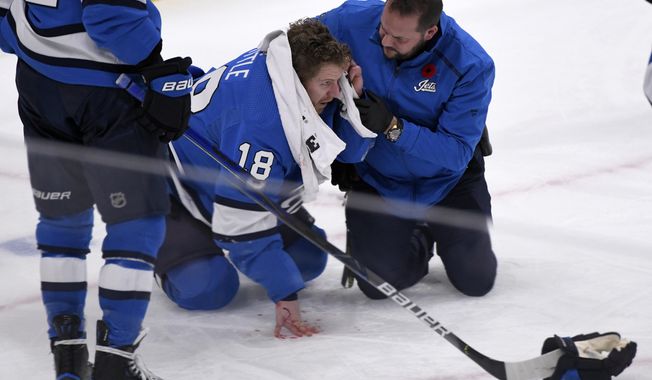 Winnipeg Jets&#x27; Bryan Little (18) is helped after getting hit in the head with the puck against the New Jersey Devils during the third period of an NHL hockey game, Tuesday, Nov. 5, 2019 in Winnipeg, Manitoba. (Fred Greenslade/Canadian Press via AP)