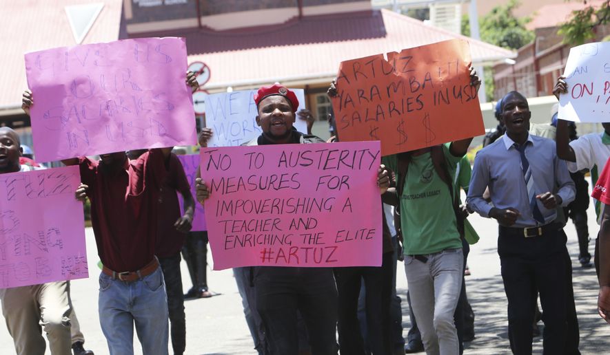 A group of government workers hold placards while protesting in Harare, Wednesday, Nov, 6, 2019. Zimbabwe police Wednesday blocked government workers from marching to protest for better salaries, a day after dozens of public hospital doctors were fired for striking for more pay. (AP Photo/Tsvangirayi Mukwazhi)