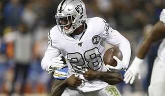 Oakland Raiders running back Josh Jacobs (28) tries to get away from Los Angeles Chargers defensive end Melvin Ingram III during the first half of an NFL football game in Oakland, Calif., Thursday, Nov. 7, 2019. (AP Photo/D. Ross Cameron)