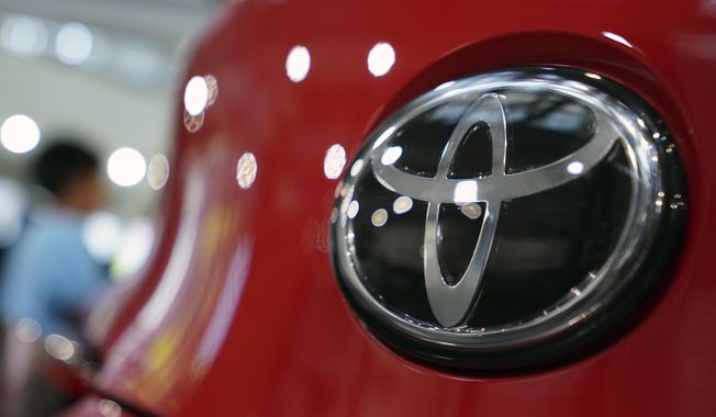 FILE - In this Aug. 2, 2019, file, photo, people walk by the logo of Toyota at a show room in Tokyo. Japan&#x27;s top automaker Toyota has seen a 1% rise in July-September profit as vehicle sales grew around the world, according to Toyota&#x27;s report on Thursday, Nov. 7, 2019. (AP Photo/Eugene Hoshiko, File)