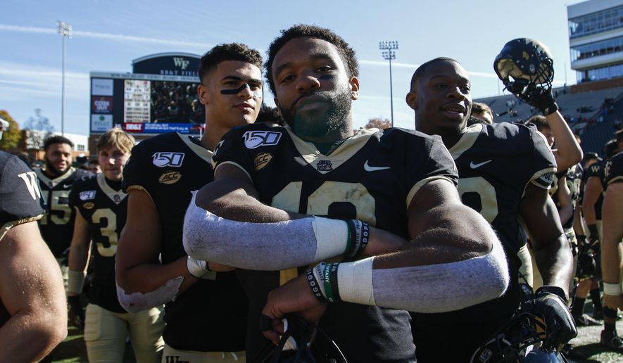 Wake Forest quarterback Jamie Newman, center, stands on the field after leading his team to a 44-10 win over North Carolina State in NCAA college football game in Winston-Salem, N.C., Saturday, Nov. 2, 2019. (AP Photo/Nell Redmond)