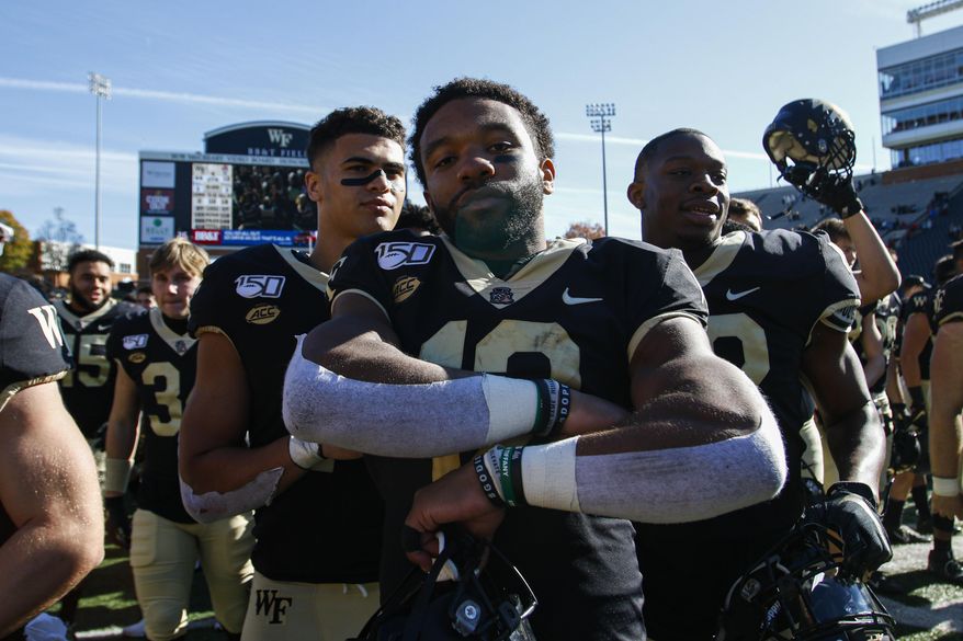 Wake Forest quarterback Jamie Newman, center, stands on the field after leading his team to a 44-10 win over North Carolina State in NCAA college football game in Winston-Salem, N.C., Saturday, Nov. 2, 2019. (AP Photo/Nell Redmond)