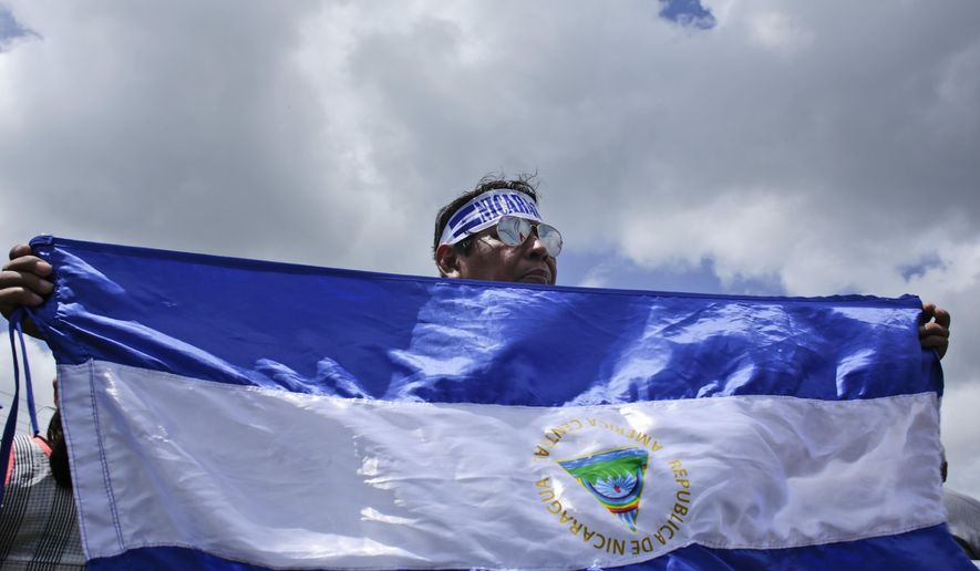FILE - In this July 30, 2018 file photo, a protester holds up a Nicaraguan flag during a demonstration supporting journalists recently attacked while covering protests demanding the resignation of President Daniel Ortega and the release of all political prisoners, in Managua, Nicaragua. The Trump administration is sanctioning three Nicaraguan officials accused of human rights abuses, election fraud and corruption, announced on Thursday, Nov. 7, 2019 by the U.S. Department of Treasury's Office of Foreign Assets Control. (AP Photo/Arnulfo Franco, File)