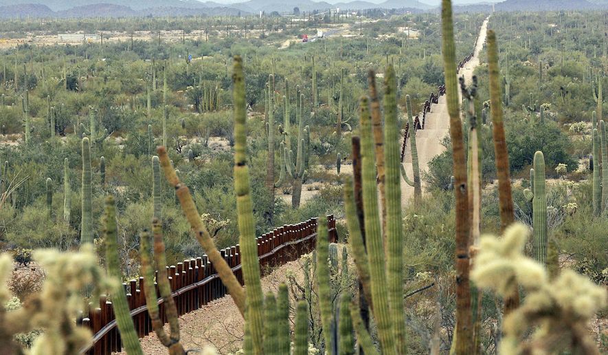 FILE - This Feb. 17, 2006 file photo, shows a fence separating Organ Pipe Cactus National Monument, right, and Sonyota, Mexico, running through Lukeville, Ariz. Environmental and other activists say they'll gather on the U.S.-Mexico border at the Organ Pipe Cactus National Monument in Arizona on Saturday, Nov. 9, 2019, to protest plans by the Trump administration to build a wall there. Laiken Jordahl of the Center for Biological Diversity says the 30-foot barrier will block wildlife migration, destroy sacred sites and imperil endangered species. (AP Photo/Matt York, File)
