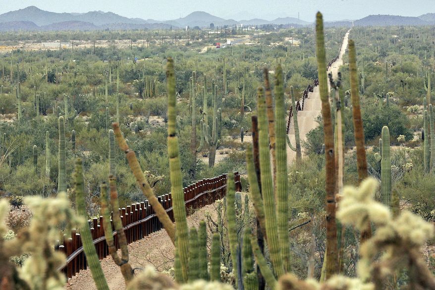 FILE - This Feb. 17, 2006 file photo, shows a fence separating Organ Pipe Cactus National Monument, right, and Sonyota, Mexico, running through Lukeville, Ariz. Environmental and other activists say they'll gather on the U.S.-Mexico border at the Organ Pipe Cactus National Monument in Arizona on Saturday, Nov. 9, 2019, to protest plans by the Trump administration to build a wall there. Laiken Jordahl of the Center for Biological Diversity says the 30-foot barrier will block wildlife migration, destroy sacred sites and imperil endangered species. (AP Photo/Matt York, File)