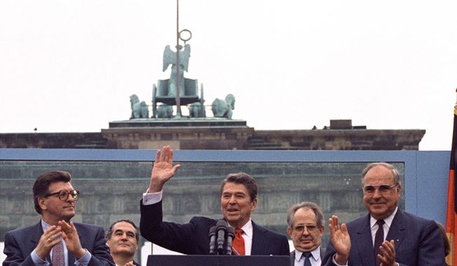 FILE - In this on Friday, June 12, 1987 file photo, U.S. President Ronald Reagan acknowledges the applause after speaking to an audience in front of the Brandenburg Gate in Berlin. Beside Reagan are the President of the German Parliament Philipp Jenninger, left, and Germany&#x27;s Chancellor Helmut Kohl, right. The U.S. Embassy in Berlin is unveiling the statue of Ronald Reagan as a tribute to the 30th anniversary of the fall of the Berlin Wall. The larger-than-life statue is being installed Friday atop the embassy&#x27;s terrace, at eye-level with the landmark Brandenburg Gate in downtown Berlin. (AP PHOTO/Ira Schwartz, File)