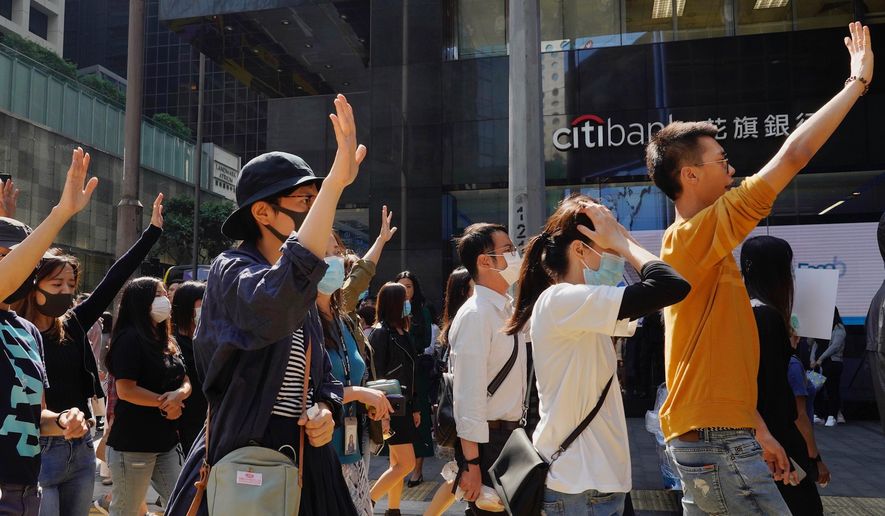 Protesters hold up their hands to represent their five demands as they take part in a memorial flash mob in Hong Kong on Friday, Nov. 8, 2019. A Hong Kong university student who fell off a parking garage after police fired tear gas during clashes with anti-government protesters died Friday, in a rare fatality after five months of unrest that intensified anger in the semi-autonomous Chinese territory. (AP Photo/Vincent Yu)