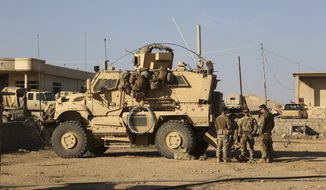 FILE - In this Feb. 23, 2017 photo, U.S. Army soldiers stand outside their armored vehicle on a joint base with Iraqi army south of Mosul, Iraq.  Iraqi security officials say 17 Katyusha rockets have hit an Iraqi air base south of the city of Mosul that houses American troops. The two officials say there are no immediate reports of casualties from the attack, which occurred on Friday, Nov. 8, 2019.  (AP Photo/ Khalid Mohammed, File)
