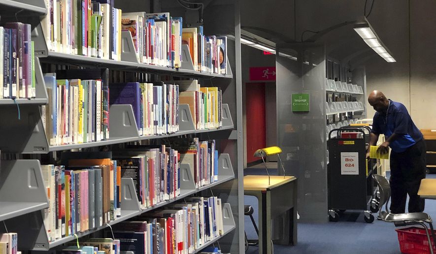 FILE - This Sept. 11, 2019, file photo, shows rows of books at the Burton Barr Central Library in Phoenix. The Phoenix Public Library system says its fine forgiveness policy takes effect Nov. 18, 2019. The City Council in September approved ending overdue fines for books, saying studies show charges on late-returned library materials do not affect how quickly they are brought back. The date the policy starts was announced Thursday, Nov. 7, 2019. (AP Photo/Anita Snow, File)