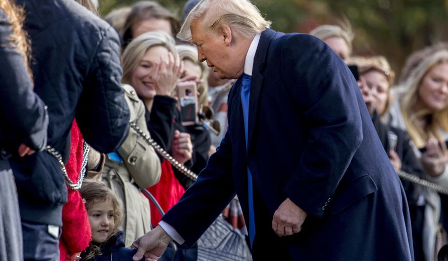 President Donald Trump pulls a girl out of the audience for a photograph on the South Lawn of the White House in Washington, Friday, Nov. 8, 2019, before boarding Marine One for a short trip to Andrews Air Force Base, Md. and then on to Georgia to meet with supporters. (AP Photo/Andrew Harnik)